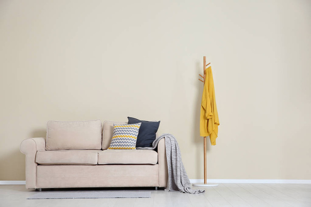 Minimalist living room interior with cozy sofa, pillows and plaid near light wall. Space for text - Φωτογραφία, εικόνα