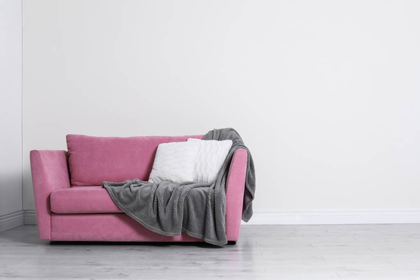 ミニマリストのリビングルームのインテリアで、居心地の良いソファ、枕、明るい壁の近くにチェック柄が備わります。テキスト用のスペース - 写真・画像