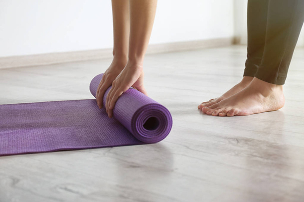Woman rolling yoga mat on floor indoors, closeup - Photo, Image