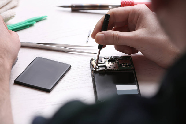 Techniker repariert Handy am Tisch, Nahaufnahme. Reparaturservice für Geräte - Foto, Bild