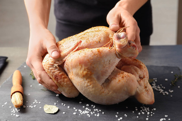 Woman preparing whole turkey at table, closeup - Fotoğraf, Görsel