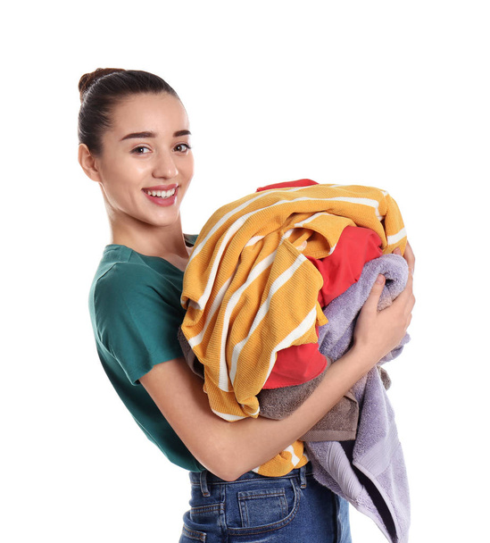 Happy young woman holding pile of dirty laundry on white background - Foto, Imagem