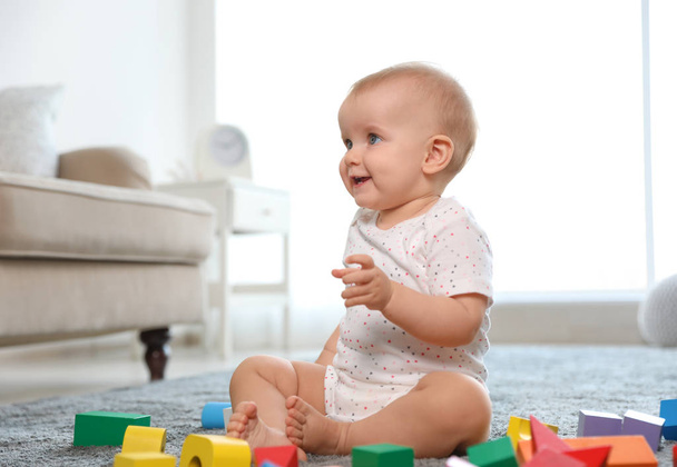 Cute baby girl playing with building blocks in room - Fotografie, Obrázek