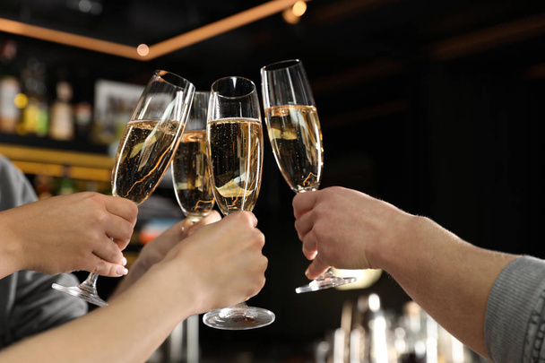 Friends clinking with glasses of champagne in bar, closeup - Photo, Image