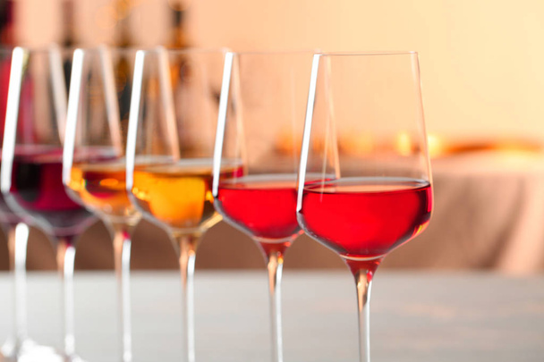 Row of glasses with different wines against blurred background, closeup - Φωτογραφία, εικόνα