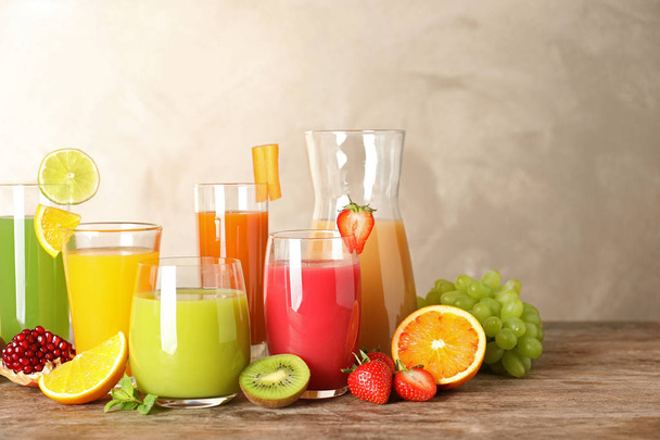 Louça de vidro com sucos diferentes e frutas frescas na mesa. Espaço para texto
 - Foto, Imagem