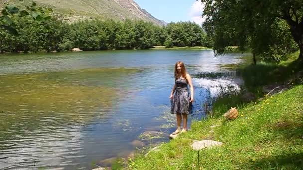 Una joven con un vestido insatisfecho explica en la orilla de un lago de montaña
 - Metraje, vídeo
