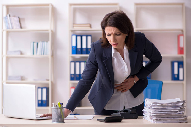 Middle-aged female employee suffering in the office  - Photo, Image