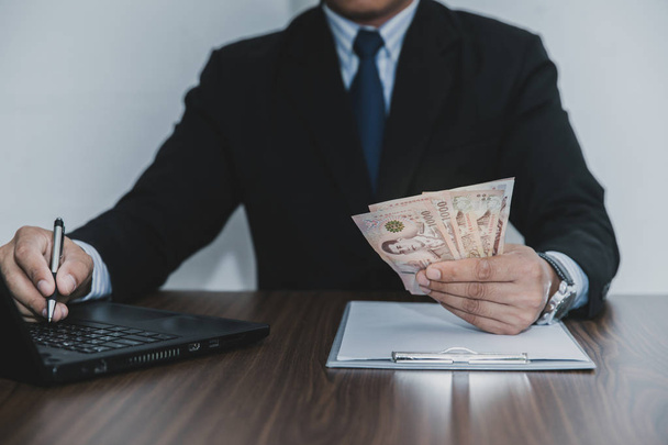 Male businessmen are sitting holding money at the desk. - Fotoğraf, Görsel