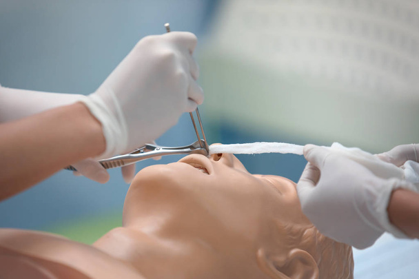 Студенты-медики используют два медицинских инструмента для моделирования носовой полости
. - Фото, изображение