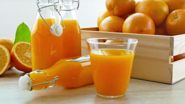 pile d'oranges fraîches dans une boîte en bois et des verres de jus - Séquence, vidéo