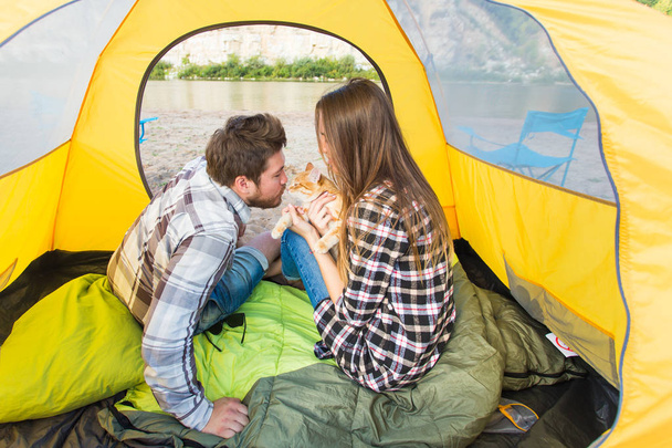 mensen, zomer toerisme en natuur concept - jong koppel rust in de tent van de camping, uitzicht vanaf binnen - Foto, afbeelding
