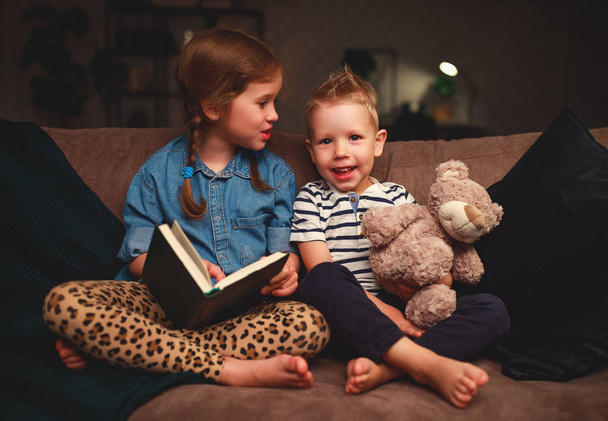 happy kids boy and girl reading a book in the evening in dar - Фото, изображение