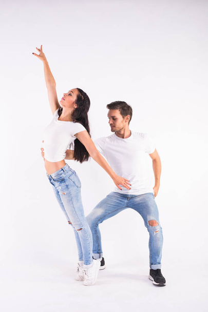 Young couple dancing social dance bachata, merengue, salsa, kizomba. Two elegance pose on white room. - Photo, Image