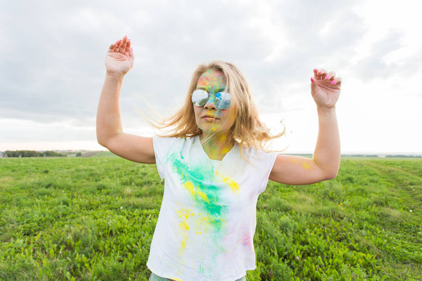 Spaß, Freude, Menschen und Urlaubskonzept - junge fröhliche Frau bei Holi-Paint-Party - Foto, Bild