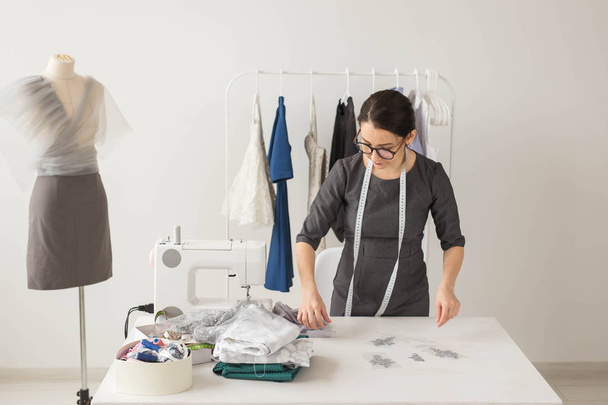 Dressmaker, fashion designer and tailor concept - young female fashion designer works in her showroom - Foto, Imagem