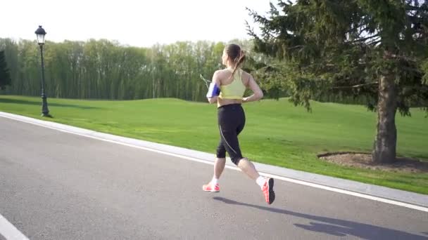 女性ランナーは空の道を走る。朝だスローモーション、バックビュー、安定したショット - 映像、動画