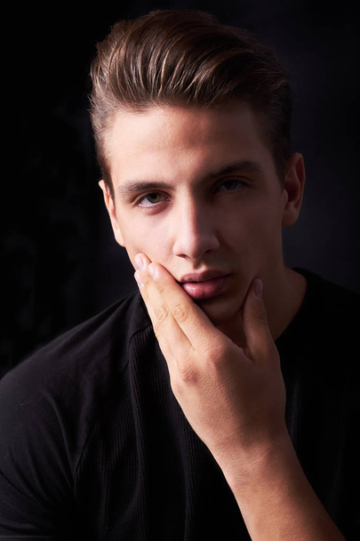 Elegant young handsome man posing on black background - Фото, зображення