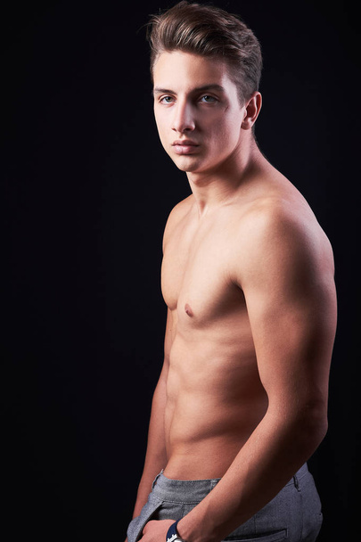 Studio portrait of handsome muscular shirtless young man isolated on black - Fotografie, Obrázek