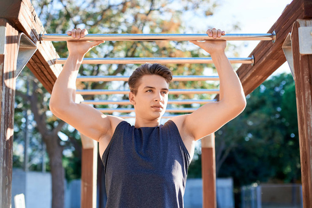 Portrait of male athlete training on horizontal bars outdoor - Φωτογραφία, εικόνα
