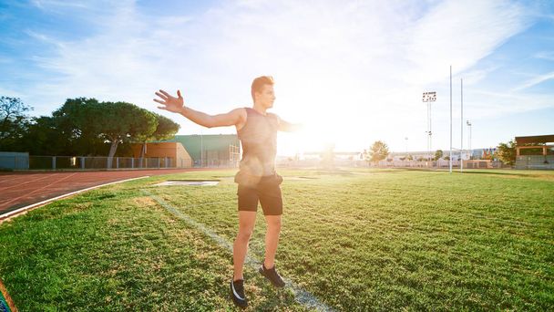 Young muscular man doing exercises on stadium - Φωτογραφία, εικόνα