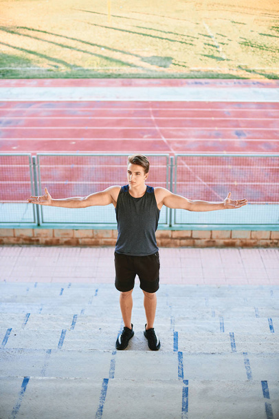 Young muscular man posing on stadium stand - Φωτογραφία, εικόνα