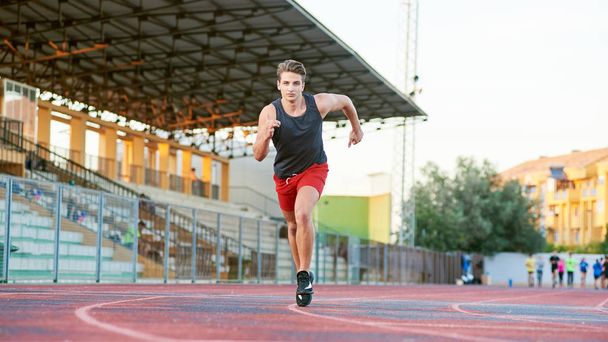 Young muscular man running on the track - Foto, afbeelding