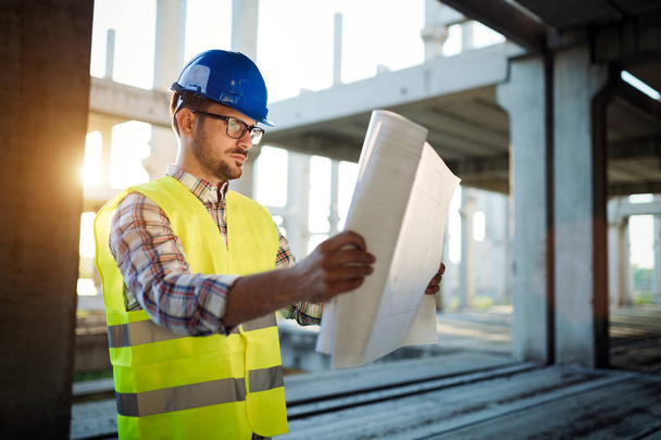 Construction engineer in hardhat with bluepront in hands - Foto, Imagen