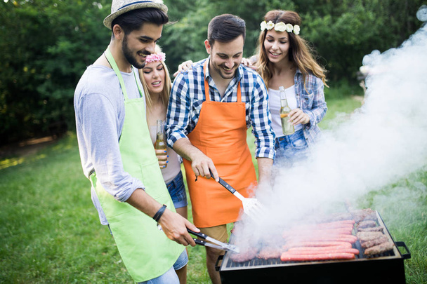 Amigos divirtiéndose asando carne disfrutando de la fiesta de barbacoa - Foto, imagen