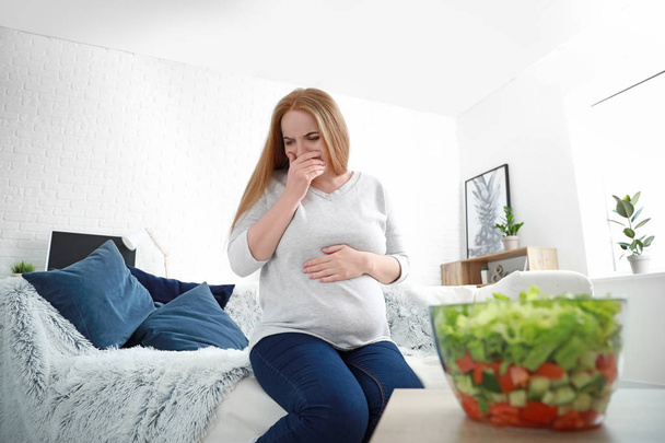 Jonge zwangere vrouw lijdt aan toxicosis thuis - Foto, afbeelding