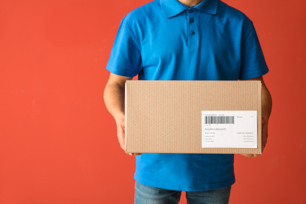 Delivery man with box on color background - Photo, Image
