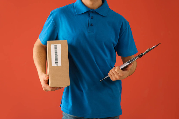 Delivery man met doos en Klembord op kleur achtergrond - Foto, afbeelding