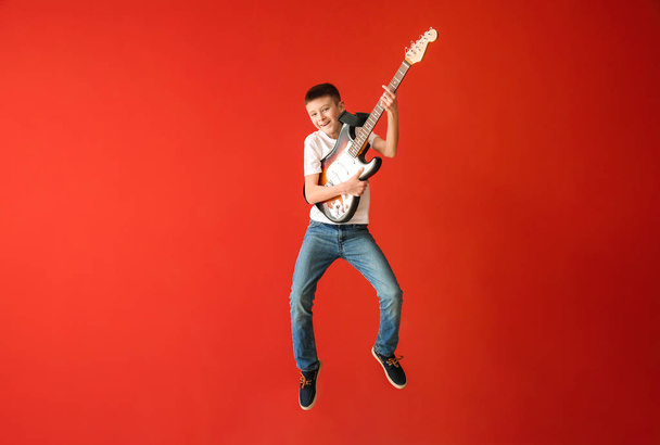Teenage boy playing guitar against color wall - Фото, зображення