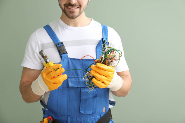 Mužský elektrikář s dráty a nástrojem na barevném pozadí, zaostřená - Fotografie, Obrázek