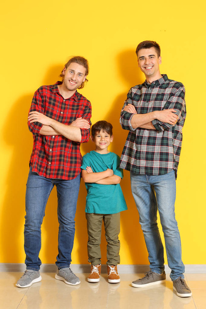 Happy gay couple with adopted child near color wall - Photo, Image