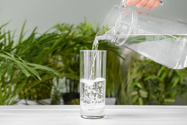 Pouring of fresh water into glass on table - Photo, Image