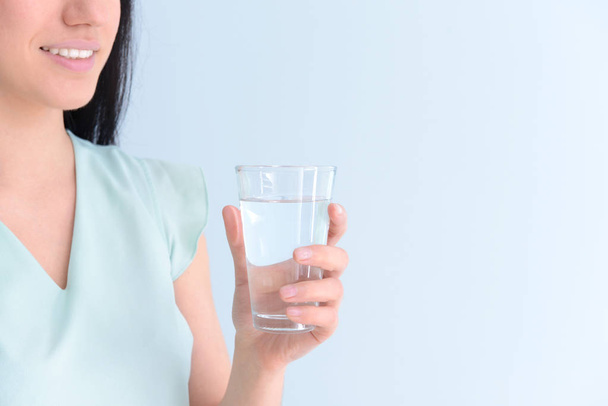 Nainen, jolla on lasi makeaa vettä valoisalla pohjalla
 - Valokuva, kuva