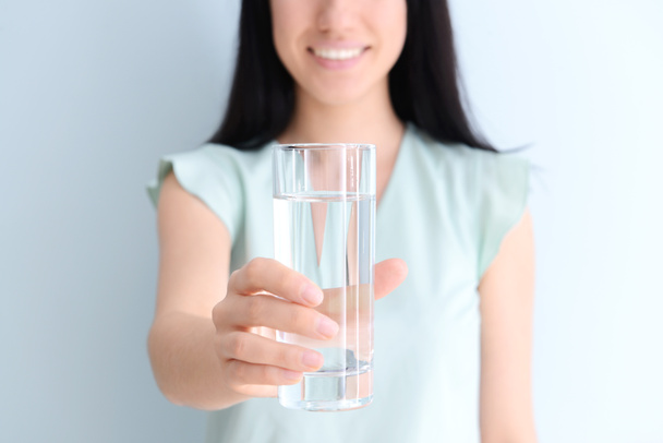 Kobieta ze szklanką świeżej wody na jasnym tle - Zdjęcie, obraz