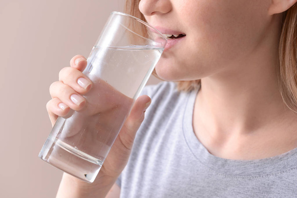 Woman drinking fresh water on color background, closeup - Fotó, kép