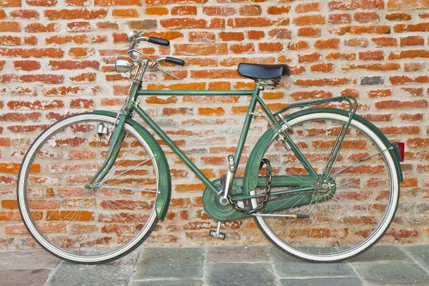 Vecchia bicicletta verde parcheggiata contro un muro di mattoni
  - Foto, immagini