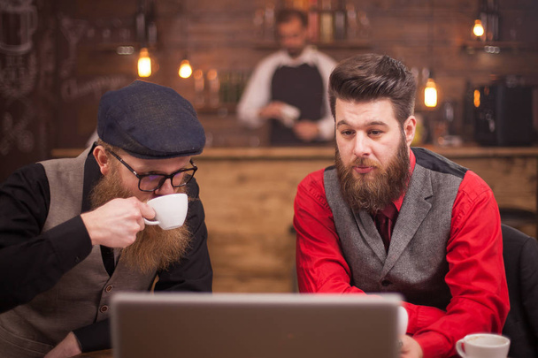 Dos exitosos hombres barbudos disfrutando de su café en un pub vintage
 - Foto, imagen