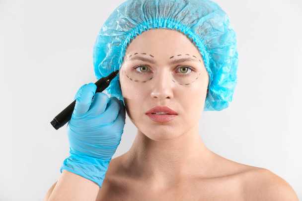 Chirurgien plastique appliquant marquage sur le visage féminin sur fond clair
 - Photo, image