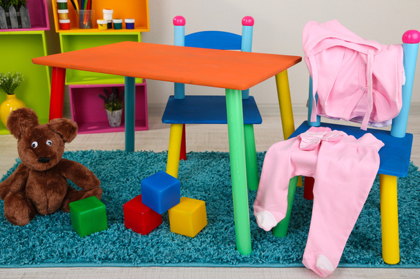 Small and colorful table and chairs with baby clothes - Fotografie, Obrázek