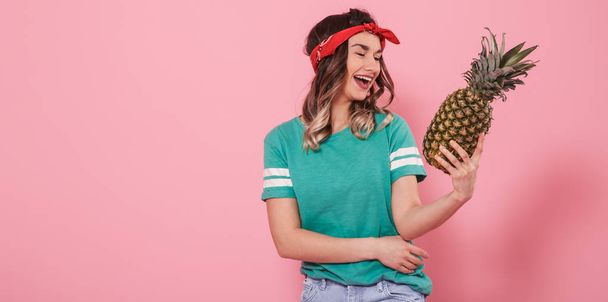 Portrait of a girl with a pineapple on a pink background - Φωτογραφία, εικόνα