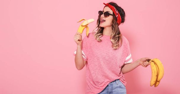 Πορτρέτο ενός κοριτσιού και μπανάνες που απομονώνονται σε ροζ φόντο - Φωτογραφία, εικόνα