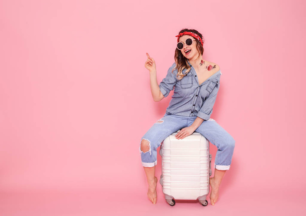 Portrait of a girl with a suitcase on a pink background - Foto, Imagem