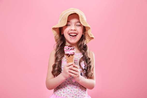 Porträt eines kleinen fröhlichen Mädchens mit Eis auf farbigem Hintergrund - Foto, Bild