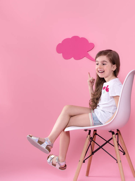 Linda niña con un icono de un discurso sobre un fondo rosa
 - Foto, imagen