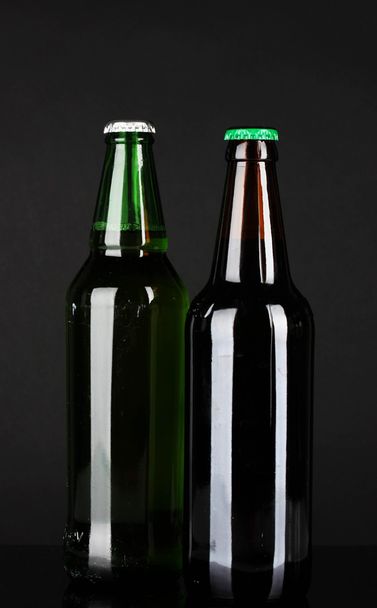 暗い背景にビールびん - 写真・画像