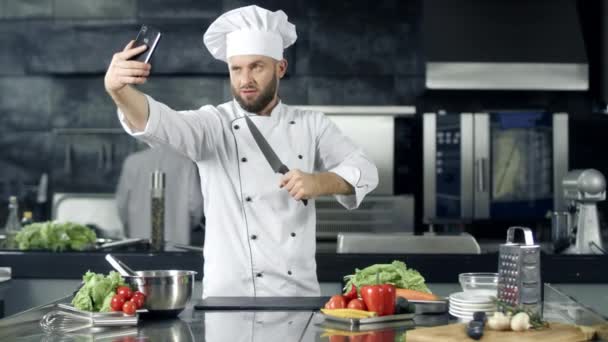 Mężczyzna szef kuchni robienia zdjęć selfie w kuchni. Profesjonalny szef kuchni z nożem - Materiał filmowy, wideo
